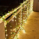 Guirlanda de luzes com folhas verdes decorando varanda à noite, ideal para ambientes externos e festas