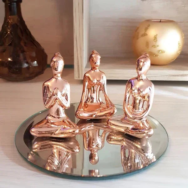 Três estátuas douradas de Buda em pose de meditação sobre base espelhada, decoração zen e minimalista